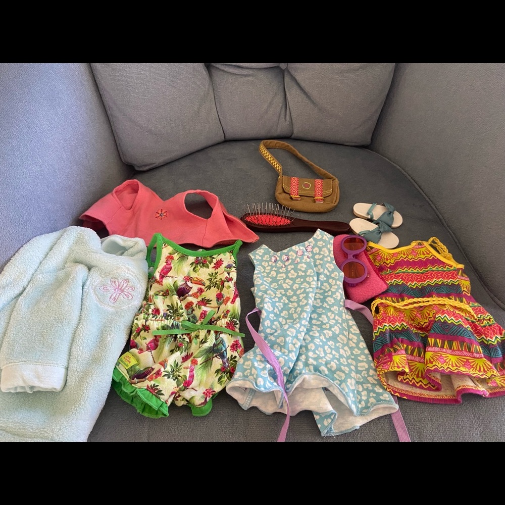 assortment of american girl doll clothes and hairbrush